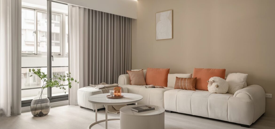 沐馨窗簾 奶灰色蛇形紗簾在客廳的效果展示 搭配奶茶色牆面與米色豆腐沙發與橘色抱枕搭配