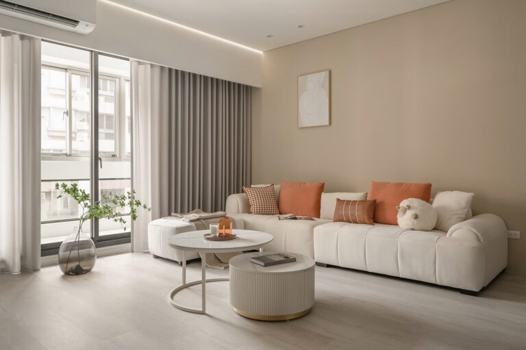 沐馨窗簾 奶灰色蛇形紗簾在客廳的效果展示 搭配奶茶色牆面與米色豆腐沙發與橘色抱枕搭配