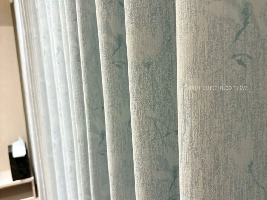 LOGO案例照 (2) - 沐馨窗簾 整體為淡米杏色基底,融入自然系枝葉圖樣,花紋以同色系稍淺的色線織出,呈現低調優雅的素雅風格。圖案靜謐細膩,彷彿樹影輕拂,為空間增添一抹自然柔和的氛圍。