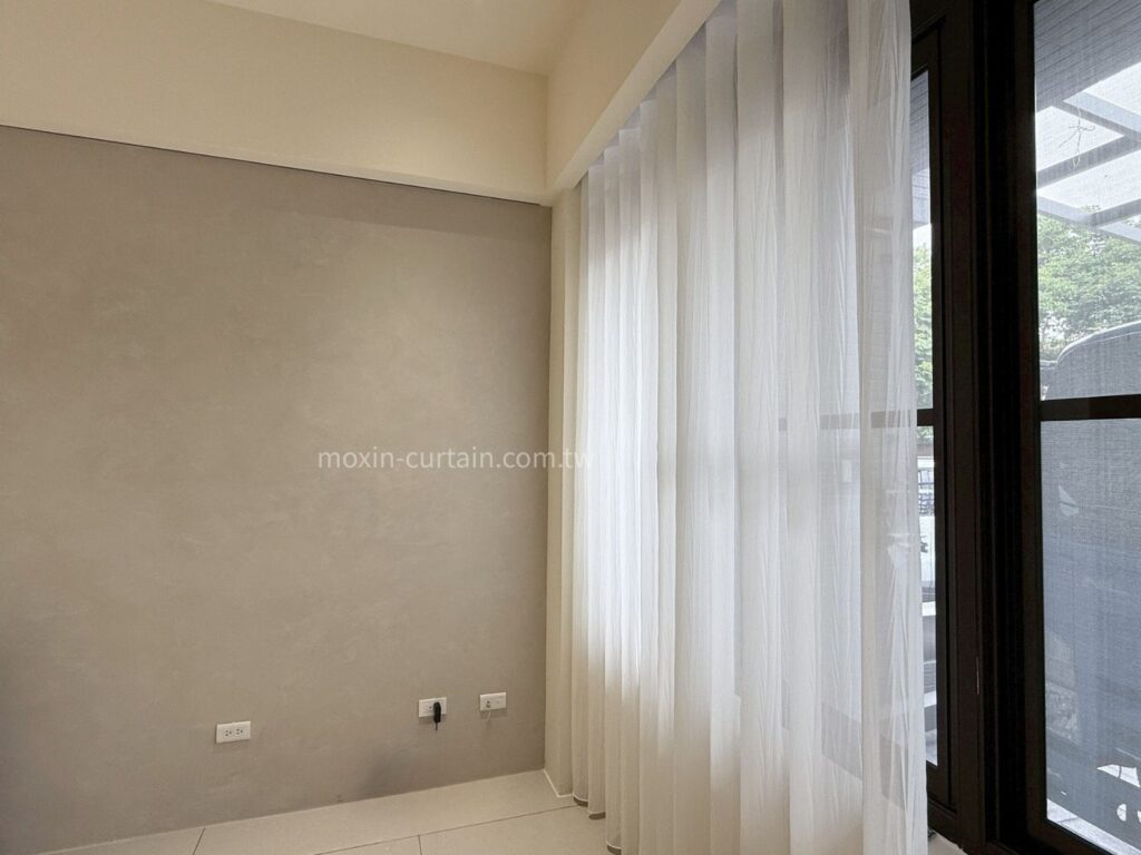 丁安琪LOGO案例照 (2) - 沐馨窗簾 沐馨窗簾從側面角度拍攝 客廳空間 灰色牆面搭配 縐褶感蛇形紗簾 微光映入